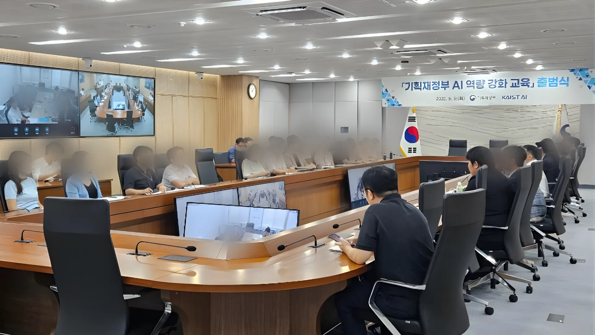 「기획재정부 AI 역량 강화 교육」 출범식이 열린 회의실. 정면에 행사 배너와 태극기가 있고 참석자들이 착석해 있다